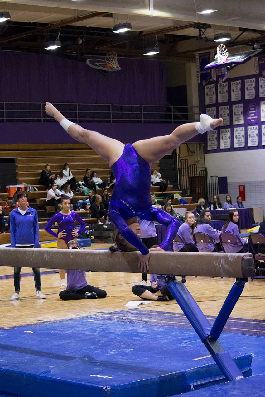 HOLD IT STEADY: Brooke Stocki (11) balances on her head during her beam routine at the Big Purple meet.