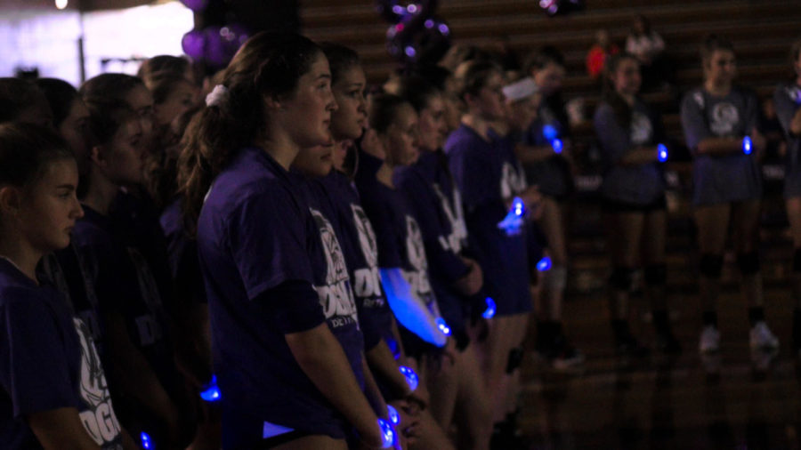 LIGHT IN THE DARK: The freshman, sophomore, and varsity teams all shown wearing glowing bracelets listening to the varsity Coach Wasik. Students bought the wristbands at the Main Street entrance during the week.