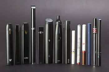 An assortment of e-cigarettes and vapes, including JUUL, PHIX, and STIG.