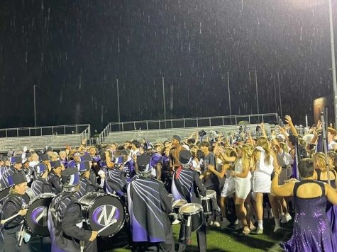 DESPITE THE RAIN: DGN players are met on the field by a swarm of spectators including the drumline, color guard and student section.